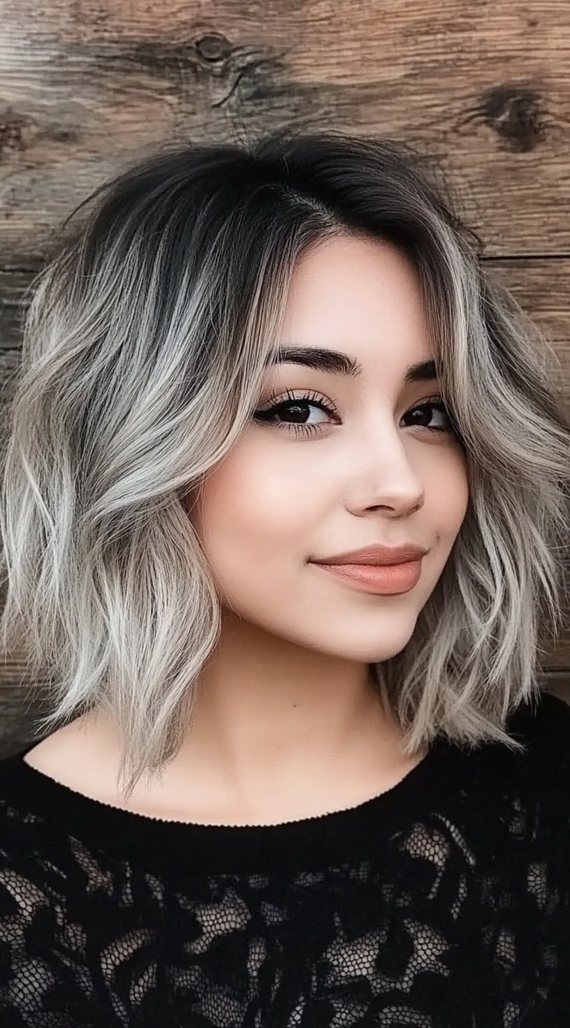 A woman with a smoky silver shag haircut, with a dark root tone and soft tousled waves.